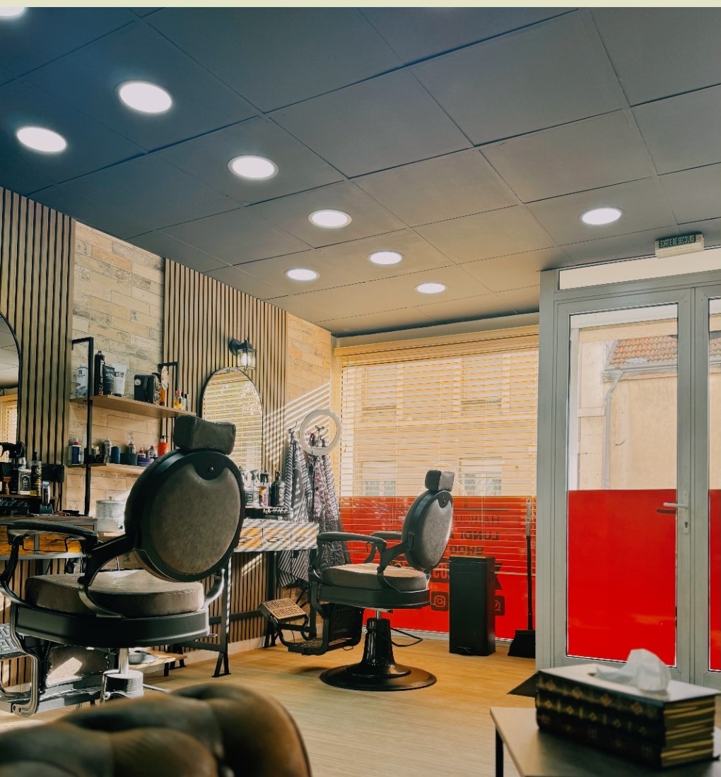 Vue d'ensemble du salon Chezel Barber : fauteuils de barbier, miroirs et mur crème
